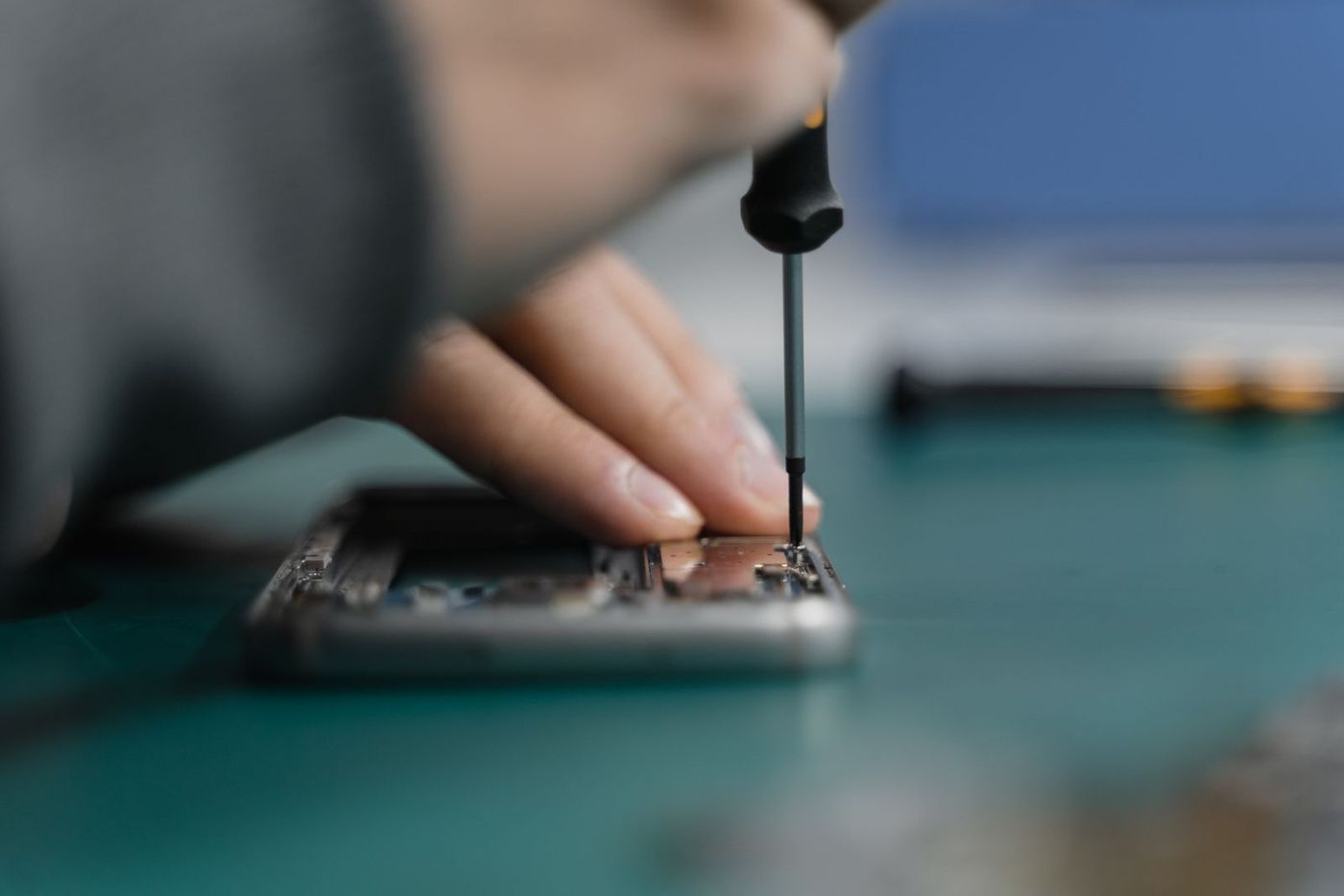 Smartphone-Reparatur: geöffnetes Handy wird mit Schraubendreher repariert